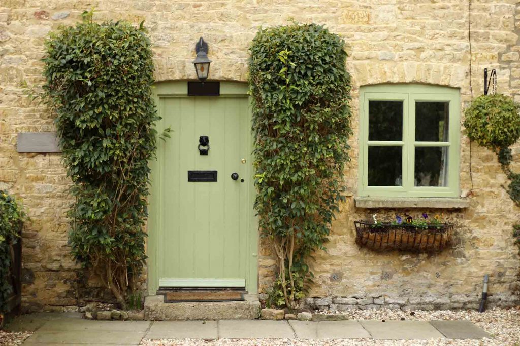 white stone cottage entrance with chartwell green door